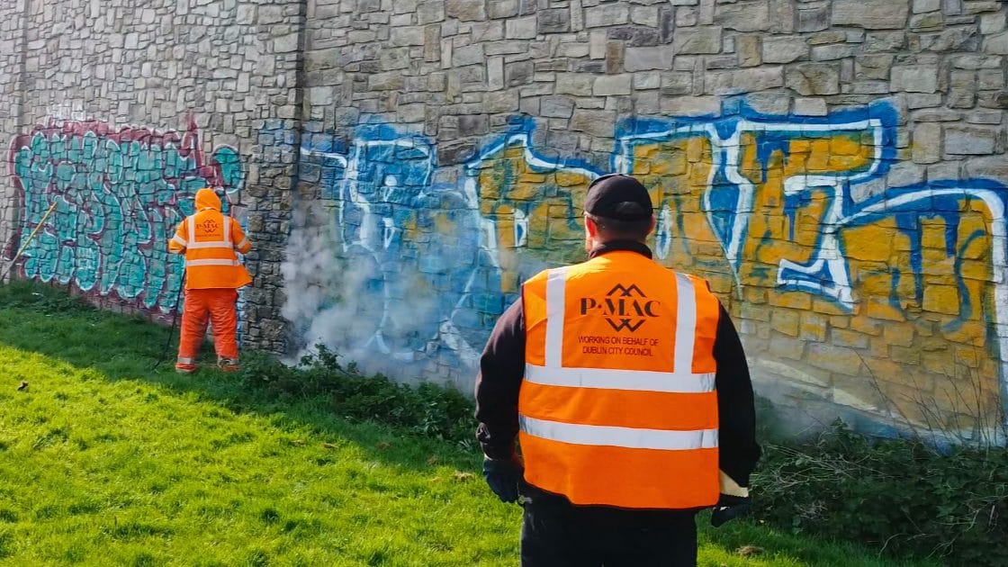 0242d82e-fc38-4b7c-957d-147a5ee13868 PMAC operatives removing large graffiti from stone wall